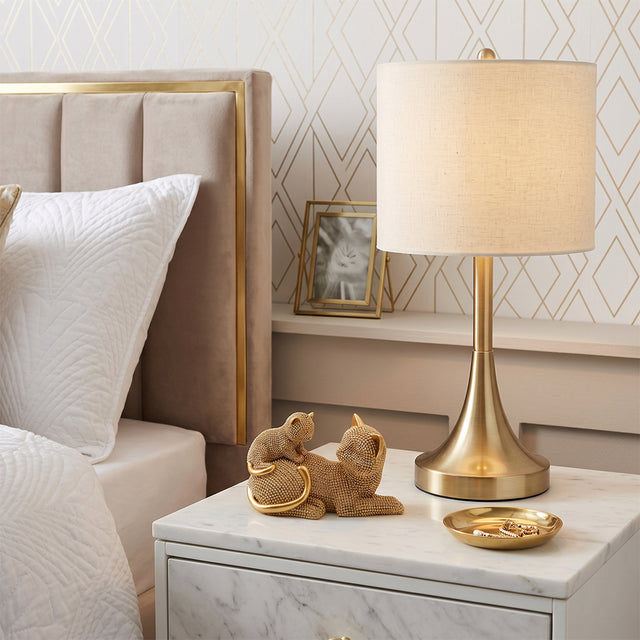Golden cat figurine on white bedroom nightstand