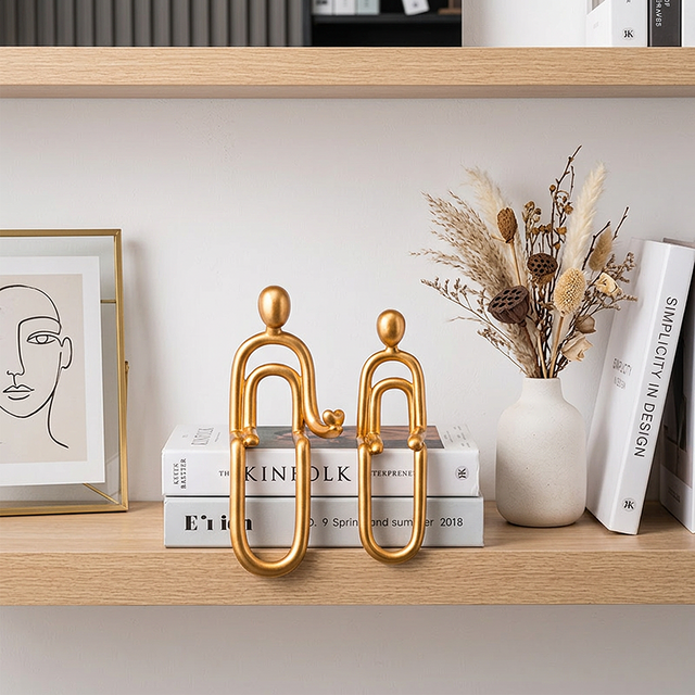 Golden human figurines bookshelf dried flowers