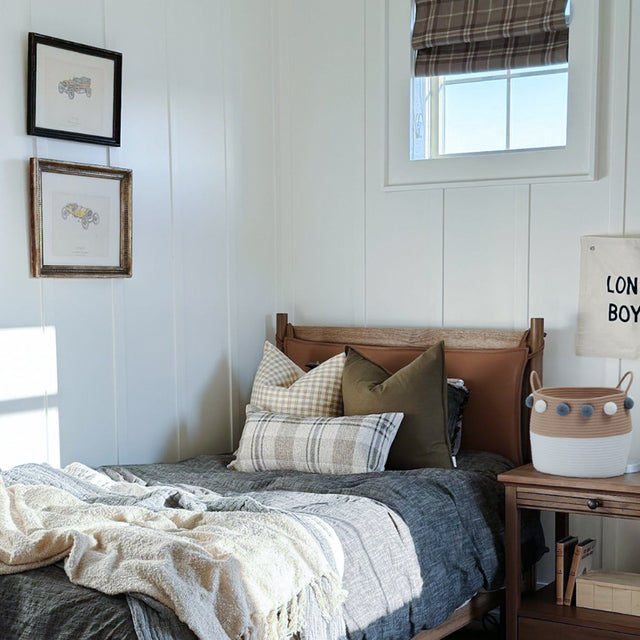 Scandinavian Rope Woven Toy Clothing Storage Basket with Pom Poms Beside the Bed