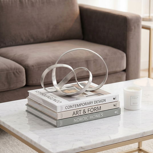 Silver ring sculpture stacked on coffee table books