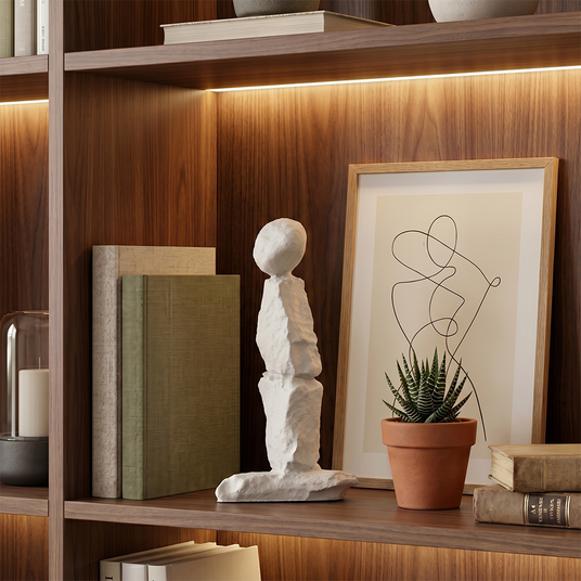 White stone sculpture on lit woodbookshelf