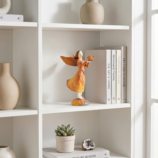 angel holding bird figurine on white bookshelf