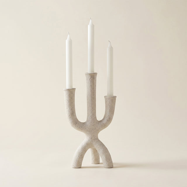beige textured three prong candle holder with candles