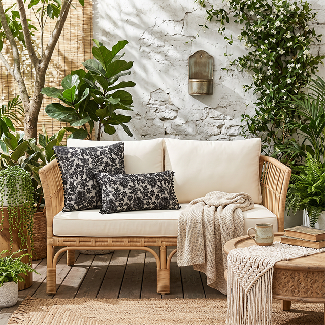 black floral pillows on rattan patio sofa with plants