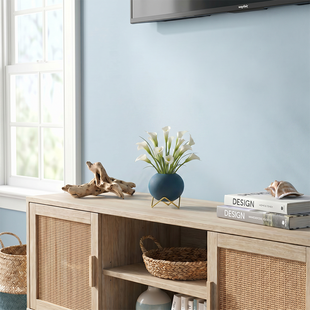 blue spherical vase with calla lilies on cabinet