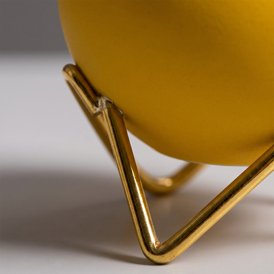 close up of gold stand and yellow vase leg