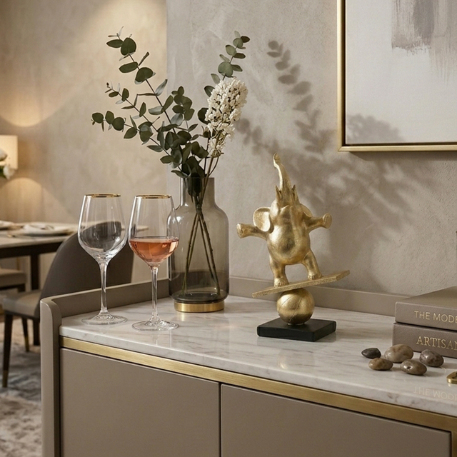 gold balancing elephant on cabinet with wine glasses