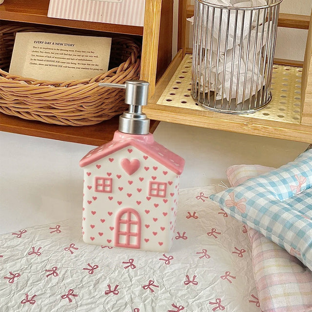 house-shaped pink ceramic soap dispenser on the table