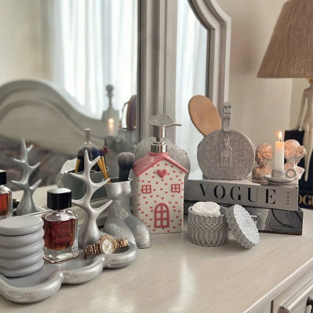 house-shaped pink ceramic soap dispenser on the tabletop