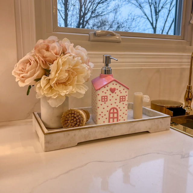 house-shaped pink ceramic soap dispenser on the tray