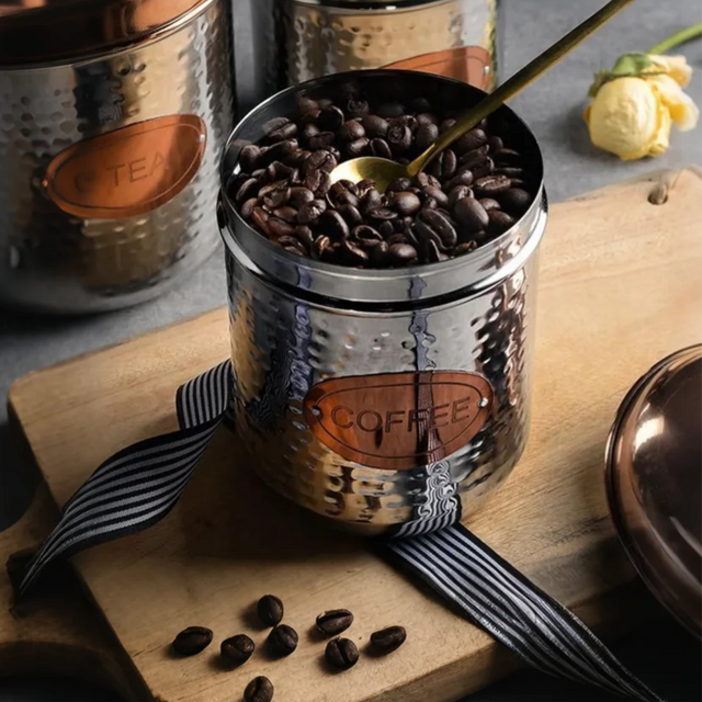 stainless steel sealed coffee storage canister with a pineapple handle storing coffee beans
