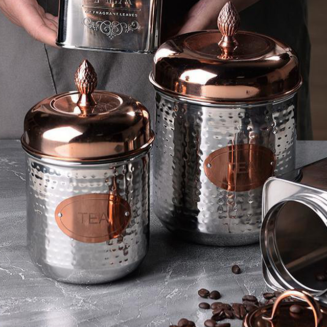 stainless steel sealed tea storage canister with a pineapple handle on the table