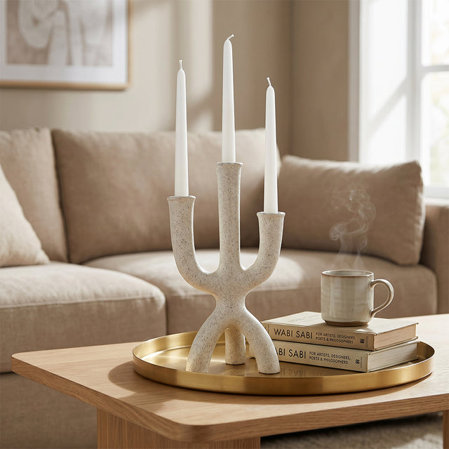 textured candle holder on gold tray with books