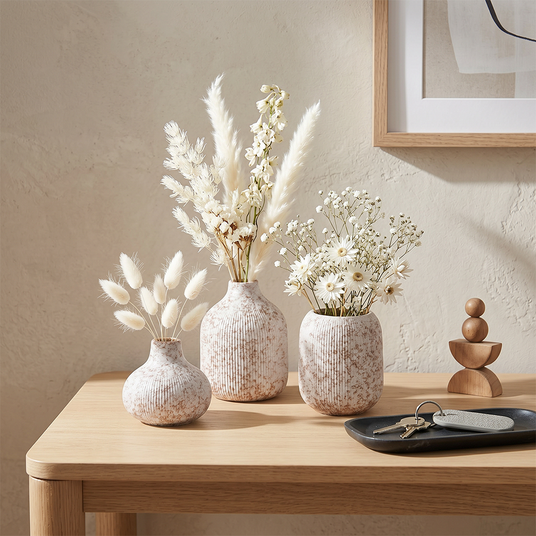 vases with white dried flowers on wooden table