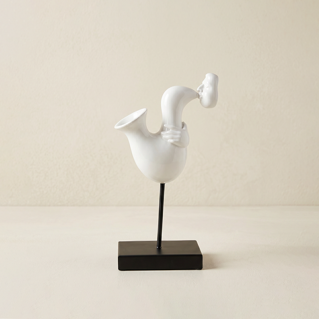 white abstract saxophone player sculpture on stand