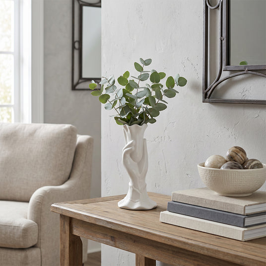 white hand vase with eucalyptus on wooden table