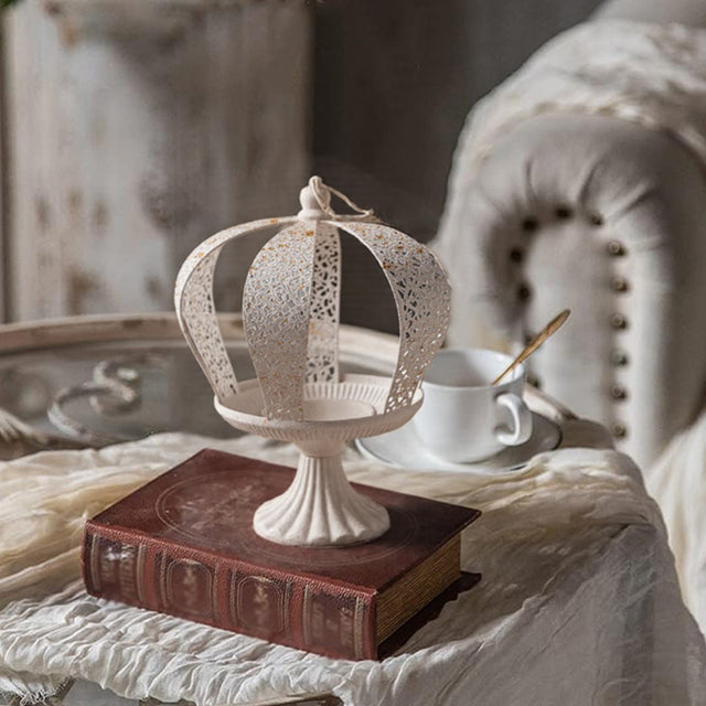 white metal crown hurricane candle holder on a book