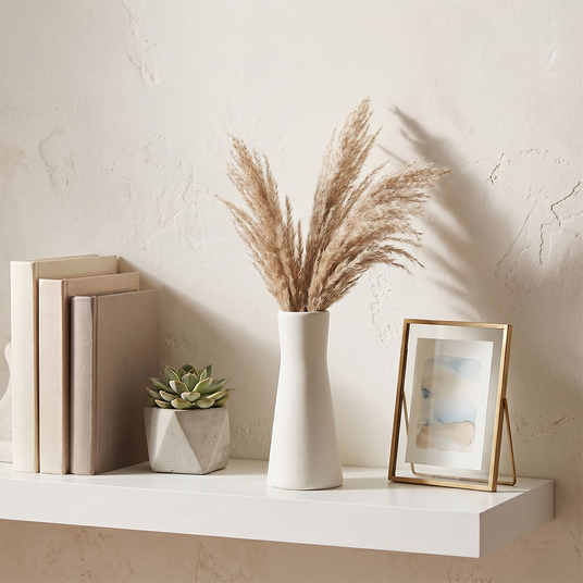 white vase with pampas on white shelf