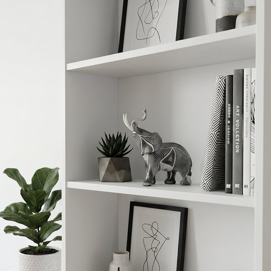 Carved elephant statue inside white open bookshelf
