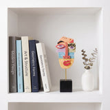 Colorful Face Sculpture On White Bookshelf