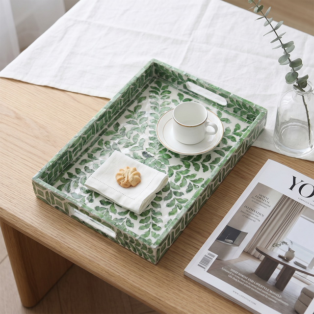 Green tray with teacup on wood tabletop