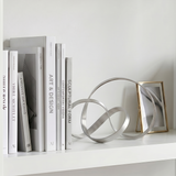 Metal loop sculpture displayed on wall mounted shelf