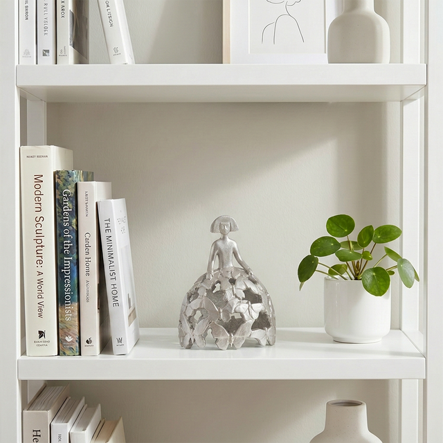 Silver figurine displayed on white bookshelf