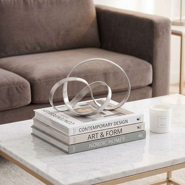 Silver ring sculpture stacked on coffee table books