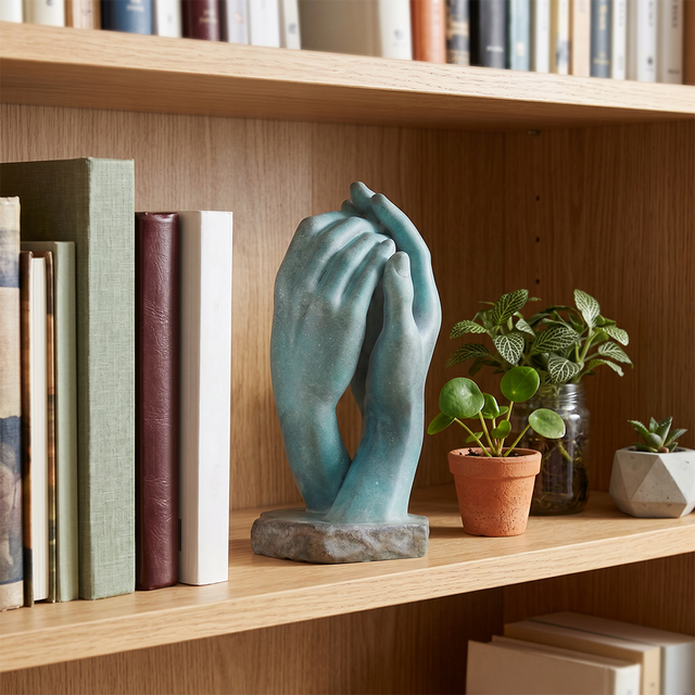 Teal hand statue inside wood bookshelf