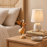 angel holding bird figurine on bedside table with lamp