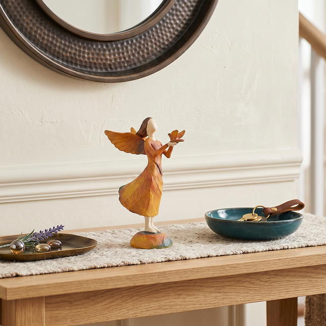 angel holding bird figurine on entryway console table