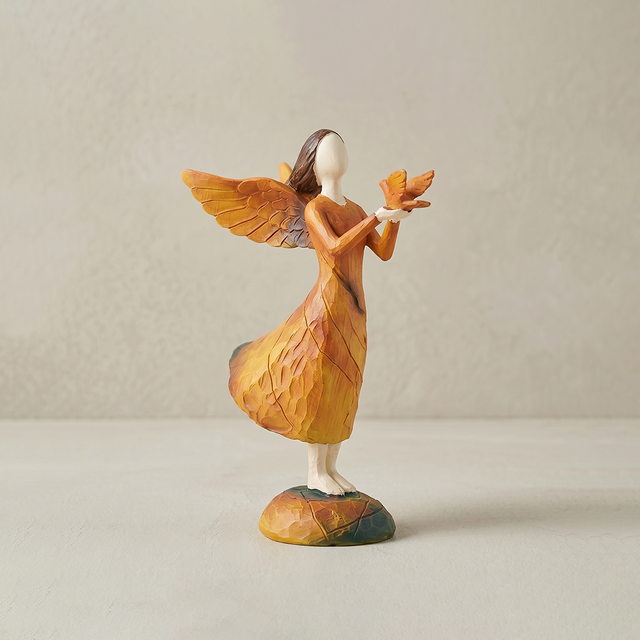 angel holding bird figurine on white background