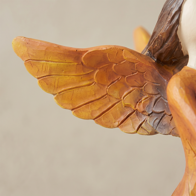 angel holding bird figurine wing texture detail