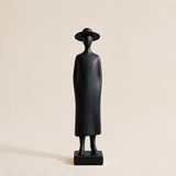black figurine wearing dress and sun hat