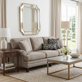 black floral pillows on beige sofa under gold mirror