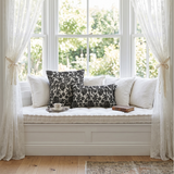 black floral pillows on white window bench with tea
