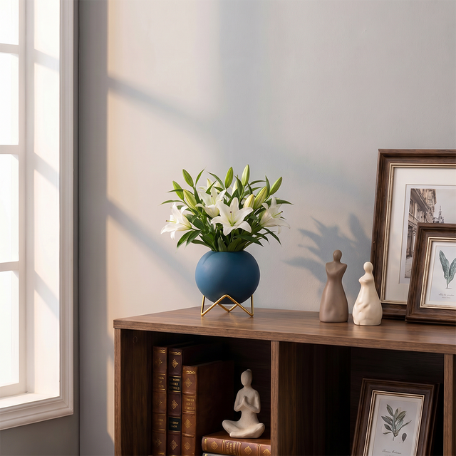 blue spherical vase with white lilies on bookshelf