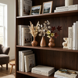brown ceramic vases on dark bookshelf