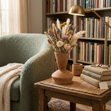 ceramic vase with fresh flowers beside bookshelf