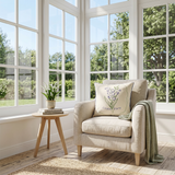 embroidered lily pillow on beige chair by window
