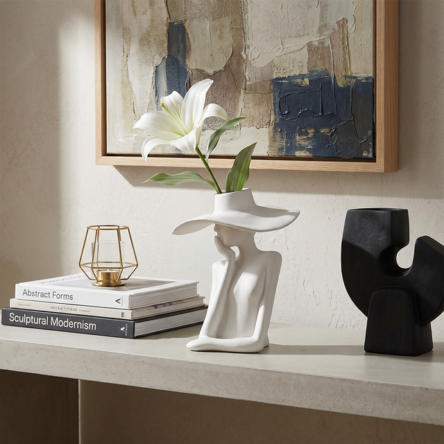 figure vase with lily beside abstract painting