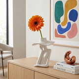 figure vase with orange flower on cabinet