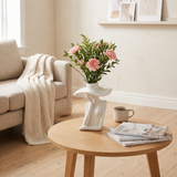 figure vase with pink flowers on coffee table