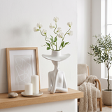 figure vase with white flowers on shelf
