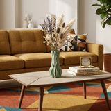 green vase with dried flowers on coffee table