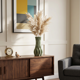 green vase with pampas grass on wooden sideboard
