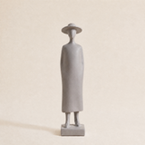 grey figurine wearing dress on neutral background