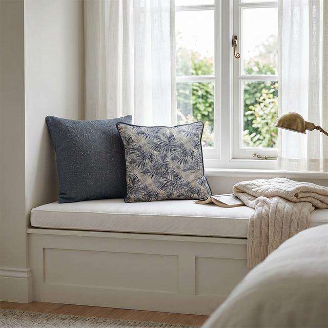 jacquard pillows on white window seat with book