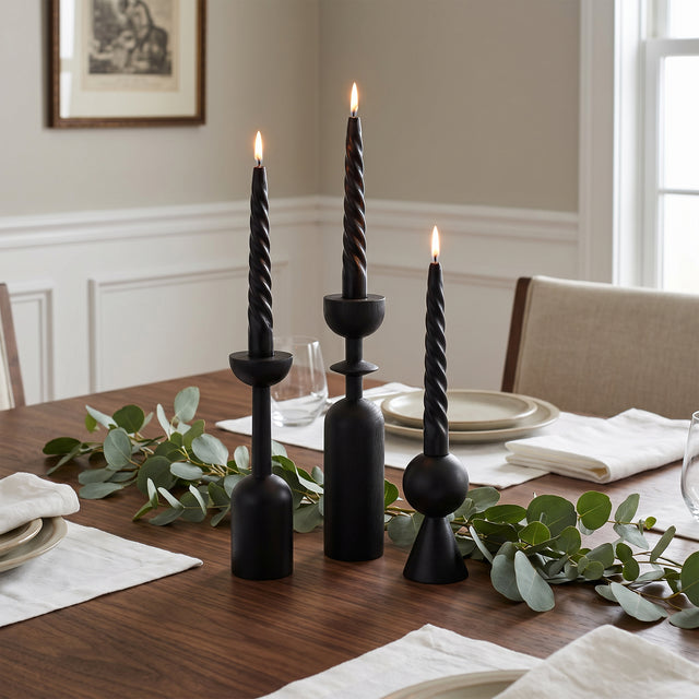 lit black candle holders on dining table with eucalyptus