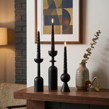 lit black candle holders on wooden mantel with art